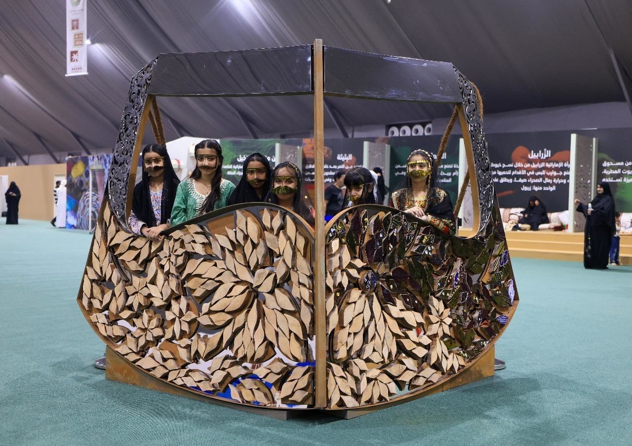 الفتيات يلتقطن الصور التذكارية  مع "مجسم البرقع" بمهرجان ليوا للرطب